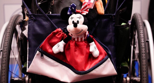 A Minnie Mouse toy hangs on the back of a wheelchair.