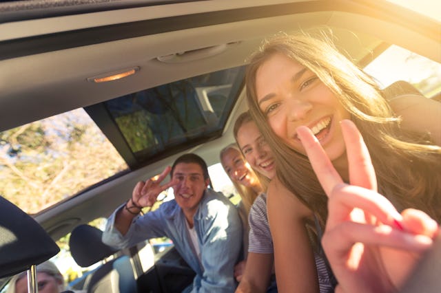 A group of teens smile and pose for a picture in a car before heading off on a spring break road tri...