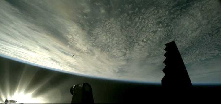 photo of earth with a tiny speck of a rocket booster in the distance.