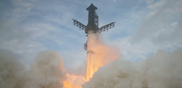 photo of a rocket on a launchpad, with its base surrounded by flame and smoke