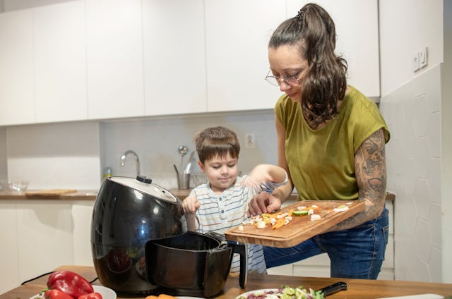 A woman and her son make dinner in the air fryer.