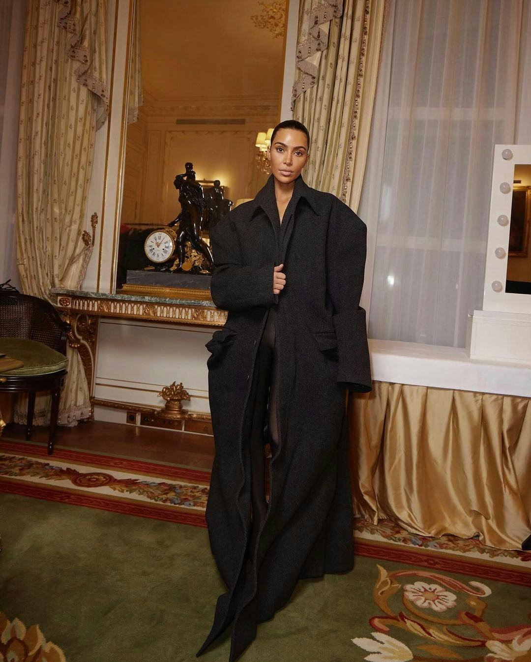 Kim Kardashian wore a black oversized coat and sheer tights.