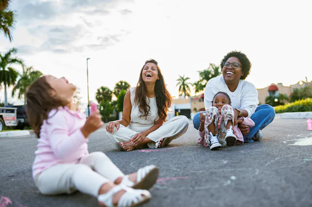 Mom friends hang out with their kids, laughing and enjoying each other.