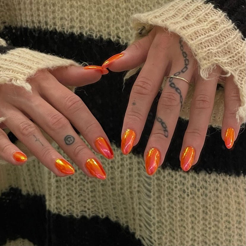Neon orange chrome nails are trending for Aries season 2024.