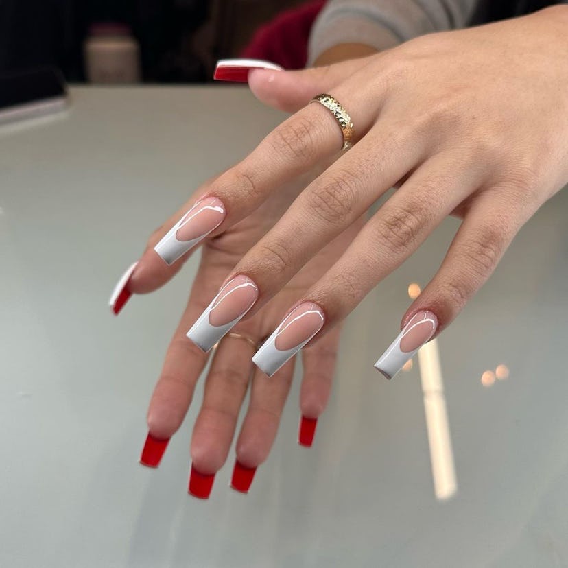 French tip nails with peekaboo red bottoms are trending for Aries season 2024.