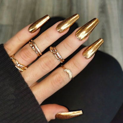 Extra-long gold chrome nails are on-trend for summer 2024.