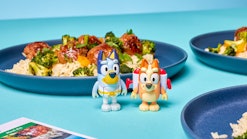 Toys of Bluey and Bingo alongside a plate made with a Home Chef meal kit.