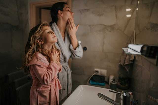 A woman and her daughter look in the mirror at their skin.
