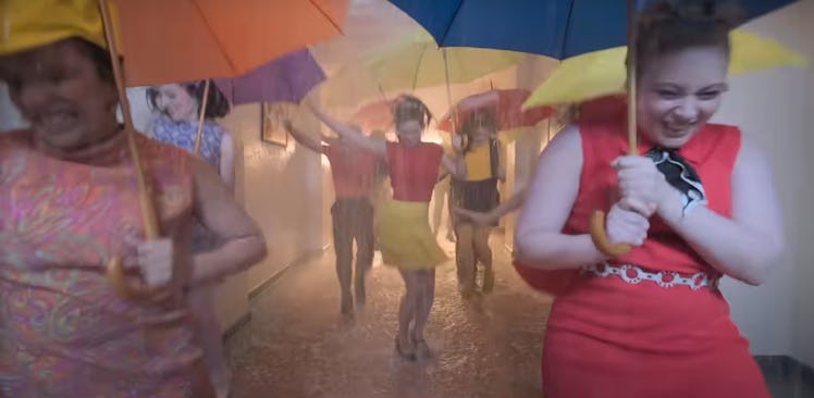 A colorful scene in the 1960s in the 2024 'Doctor Who' Season 1. Dancers hold umbrellas in the rain.