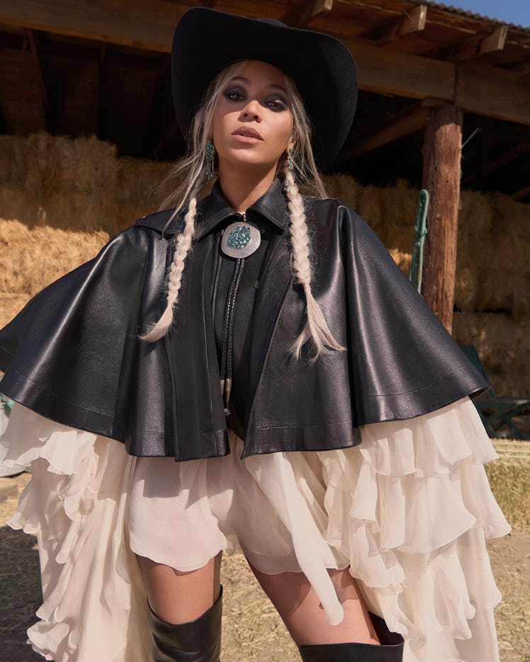 Beyonce in leather cape and white dress with cowboy hat