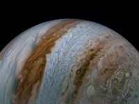 Jupiter resembles a marble. Thick bands of clouds wrap around the planet, whose equator bisects the ...