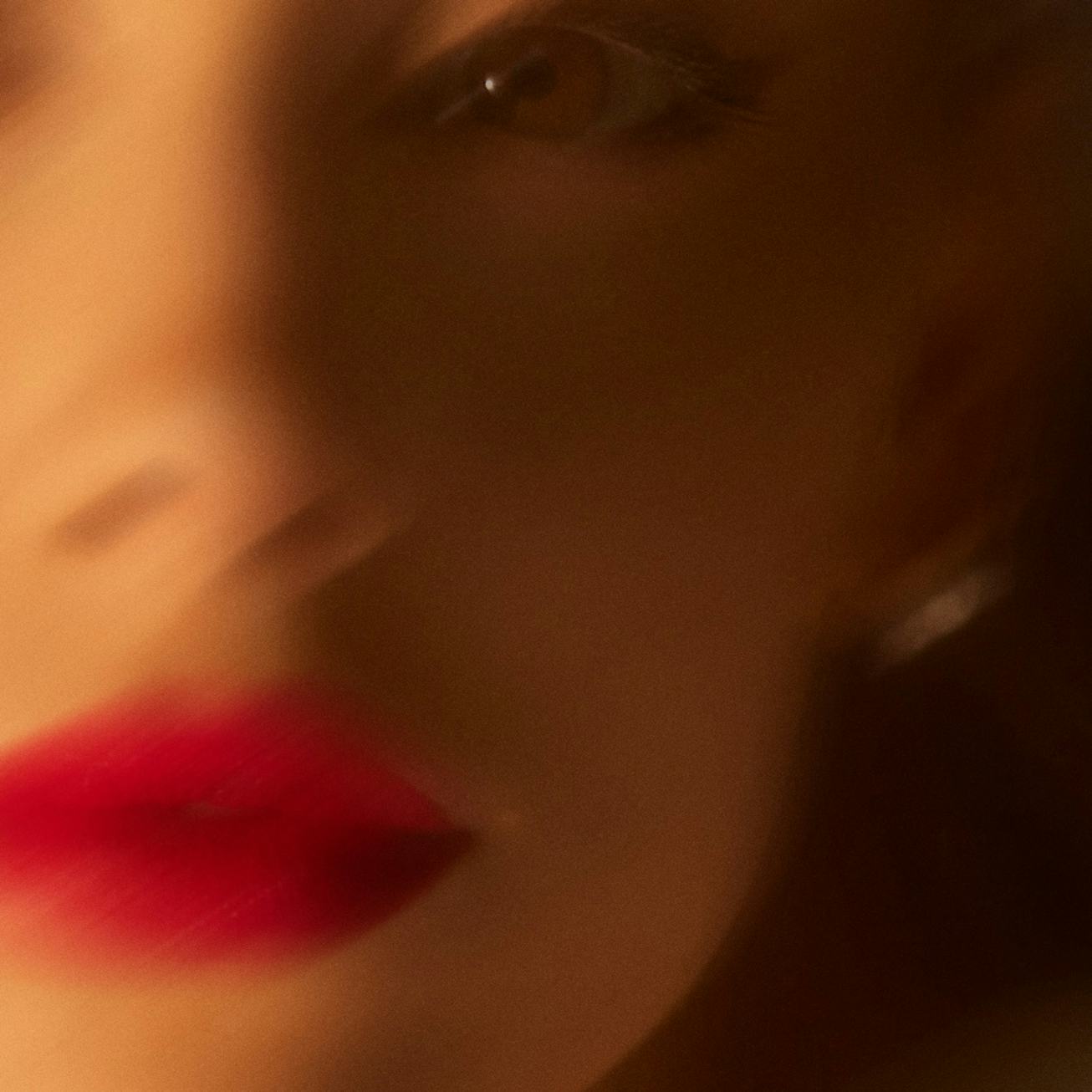 Close-up of a woman's face focused on her red lips and the side of her nose, with soft lighting and ...