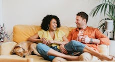 A couple sits on the couch, laughing together.