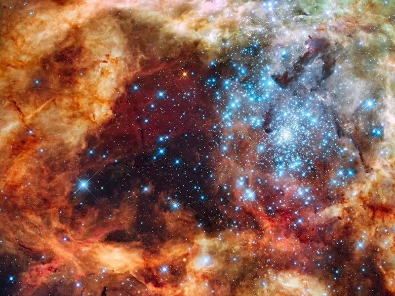 A vibrant image of a nebula with clouds of dust, gas, and stars in red, blue, and golden hues, depic...