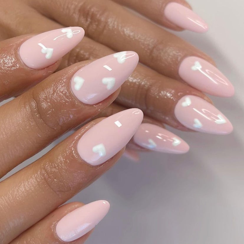 Pastel pink nails with white love heart designs are on-trend.