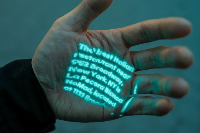 Inverse Tech Editor Ray Wong using the Humane Ai Pin's Laser Ink Display to project text surfaced by...