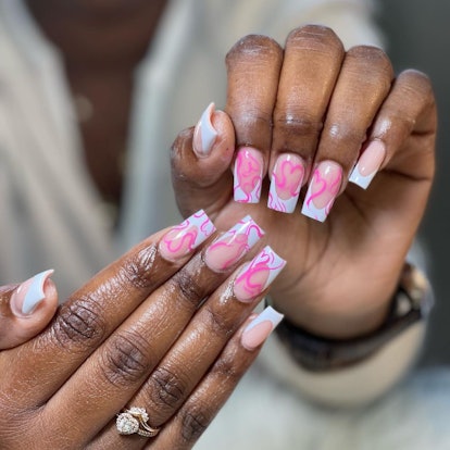 Traditional French tip nails with abstract pink hearts are on-trend for 2024.