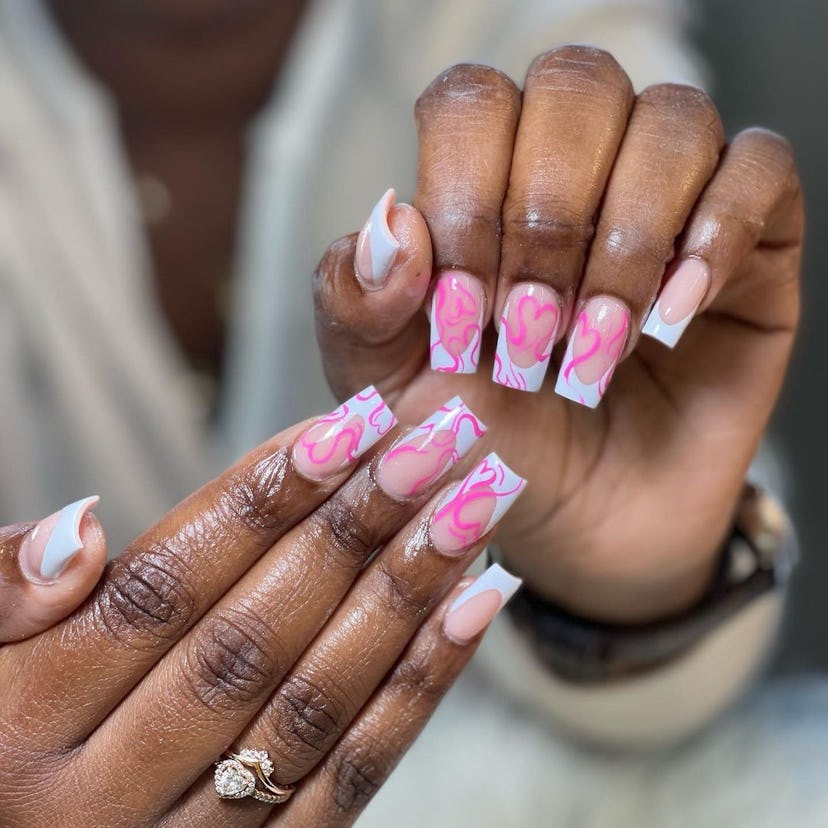 Traditional French tip nails with abstract pink hearts are on-trend for 2024.