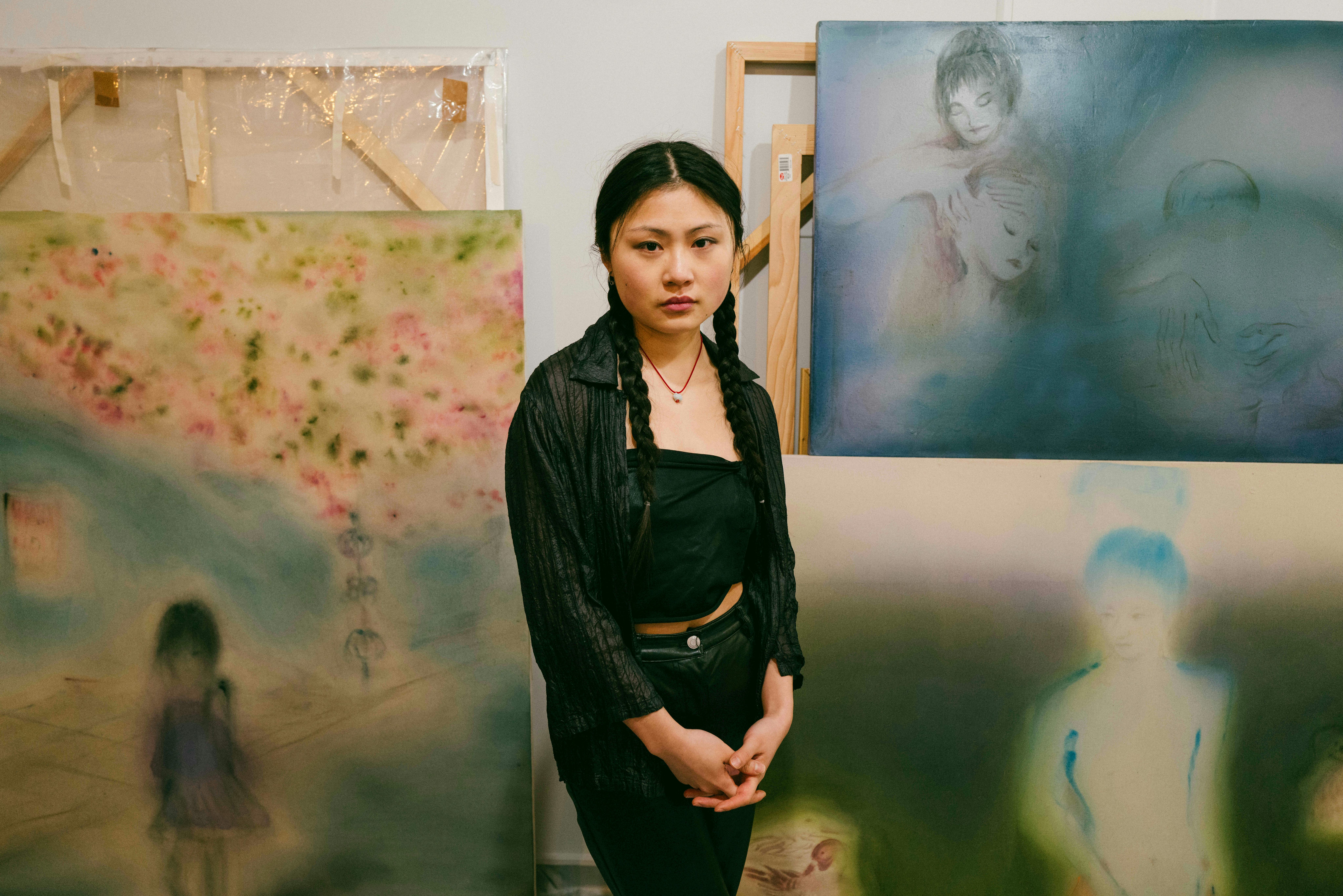 Xingzi stands in their studio amongst their works