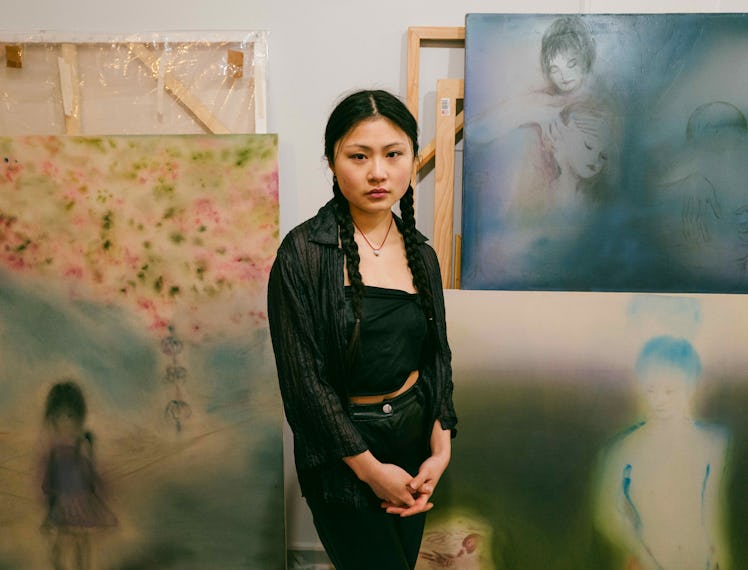 Xingzi stands in their studio amongst their works