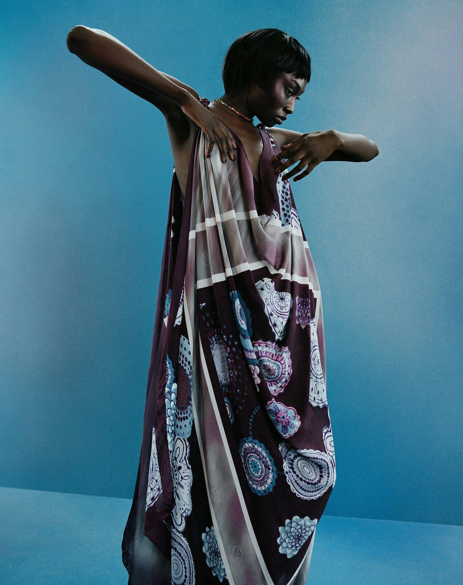 A Model wearing a paisley scarf dress against a blue backdrop