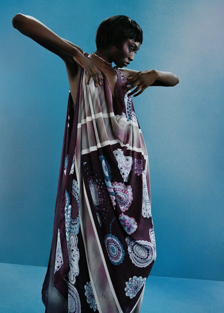 A Model wearing a paisley scarf dress against a blue backdrop