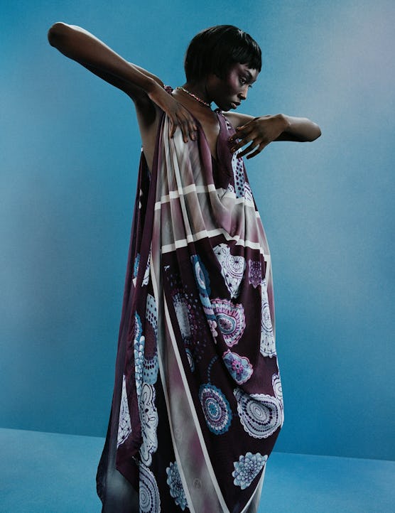 A Model wearing a paisley scarf dress against a blue backdrop