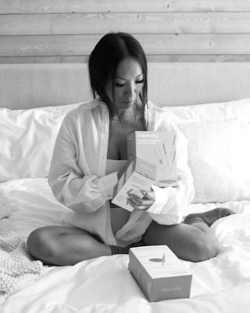Asa Akira sits on a bed looking at Frida products.