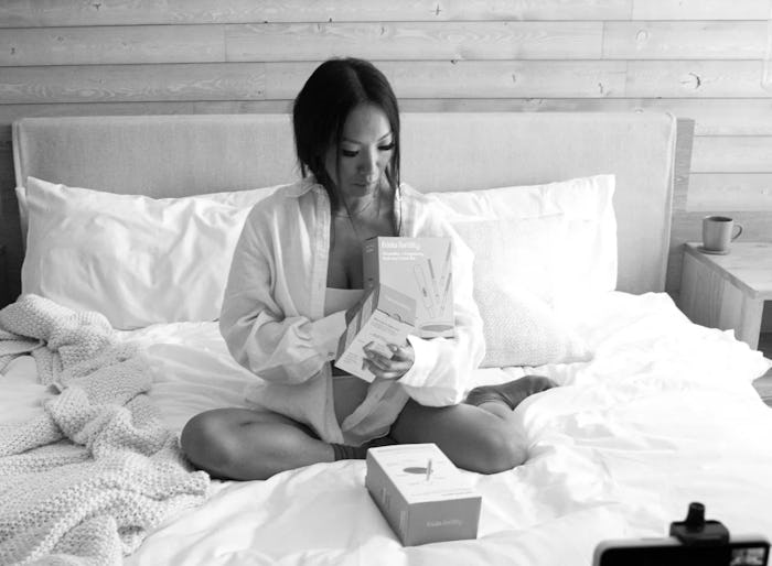 Asa Akira sits on a bed looking at Frida products.