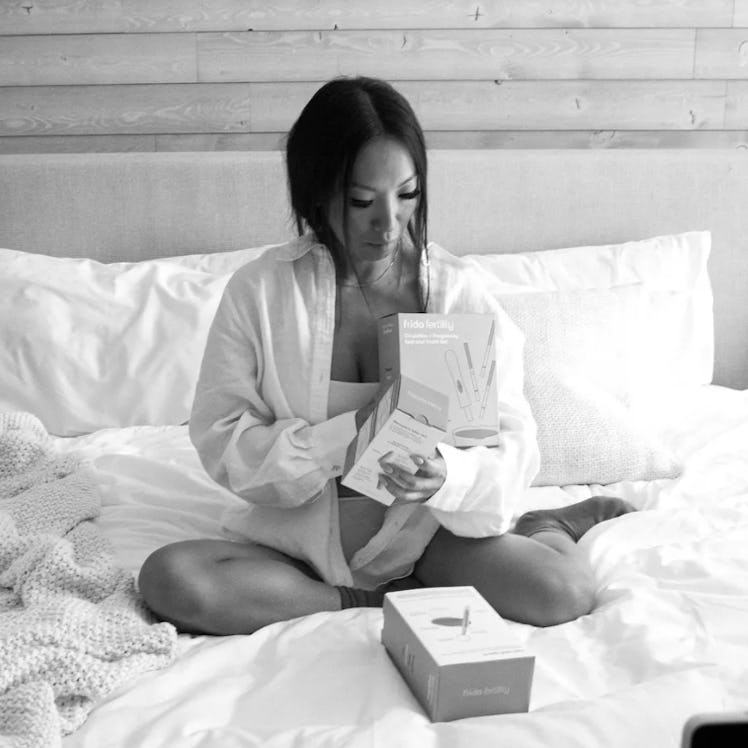 Asa Akira sits on a bed looking at Frida products.
