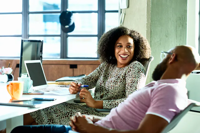A man and a woman flirt while talking at work.