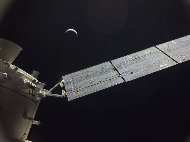 The Orion spacecraft, with the Moon in the distance. The Moon makes a downward-facing crescent again...