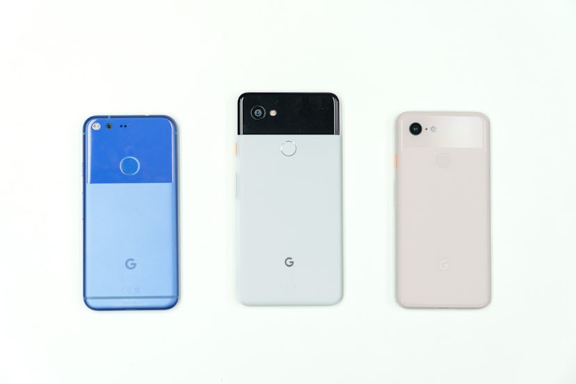 A photo of the original Google Pixel in blue, the Pixel 2 in black and white (aka panda colorway), a...