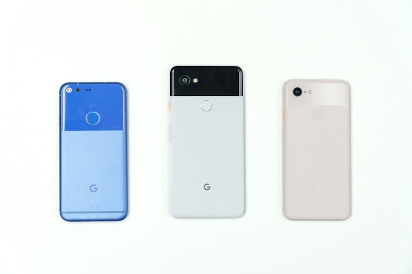 A photo of the original Google Pixel in blue, the Pixel 2 in black and white (aka panda colorway), a...