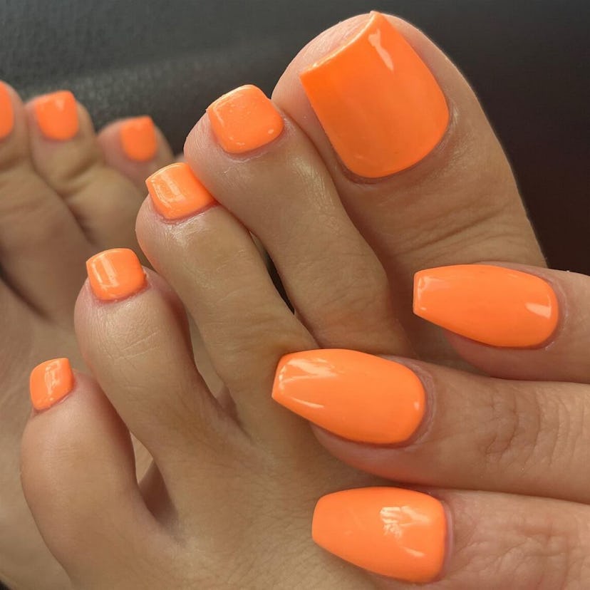 Neon orange pedicures are on-trend for summer 2024.