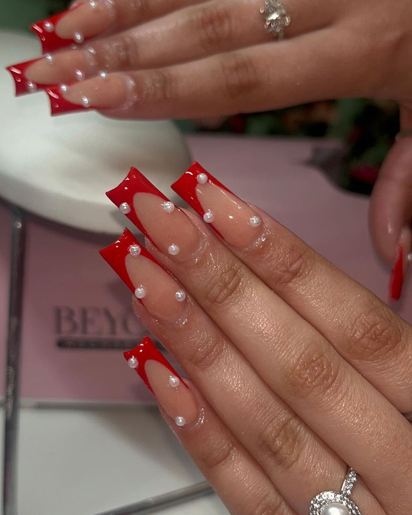 Red French tip nails with pearl adornments are on-trend.