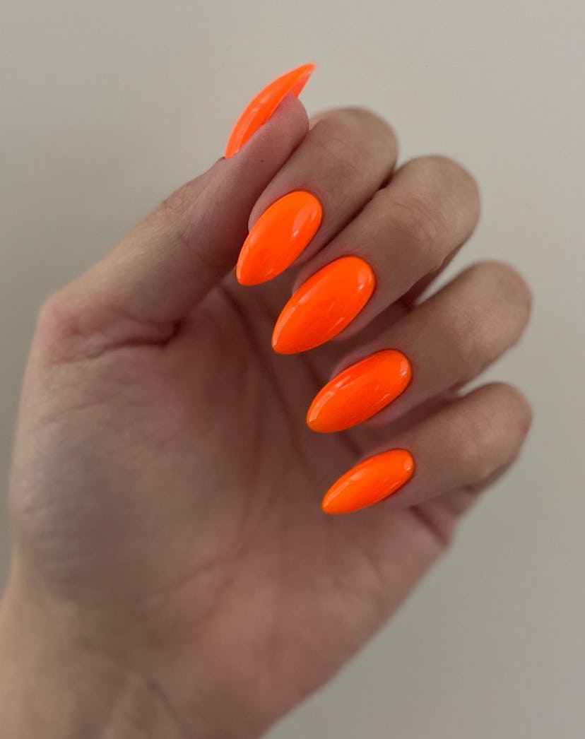 Bright orange nail polish is on-trend for summer 2024.