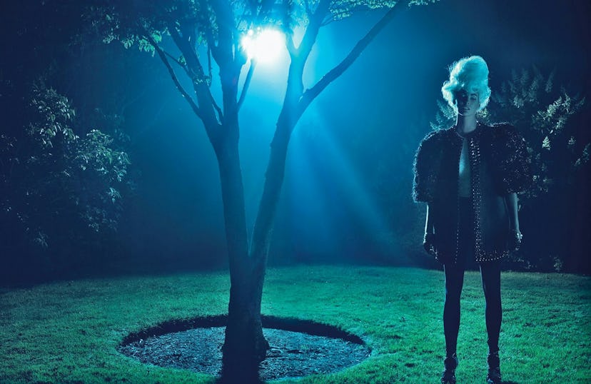 A model stands in an eery dimly lit garden