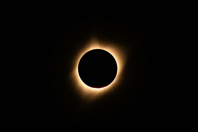 A total solar eclipse with the moon blocking the sun, creating a glowing corona in a dark sky.