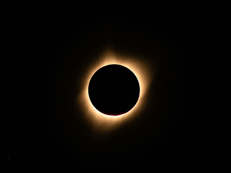 A total solar eclipse with the moon blocking the sun, creating a glowing corona in a dark sky.