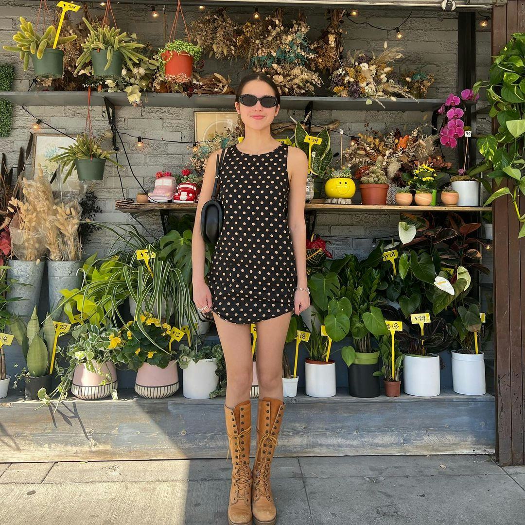 Olivia Rodrigo wears a polka dot dress and lace up boots.