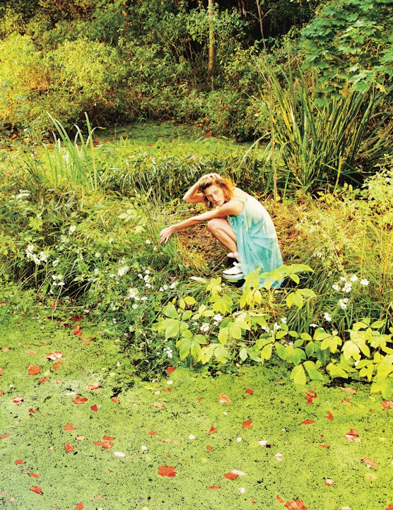 A photograph by Ryan McGinley, styled by Edward Enninful in W July 2013. A model sits in a garden