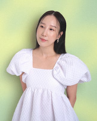 Erica Choi soft smiles wearing a white poofy sleeved dress