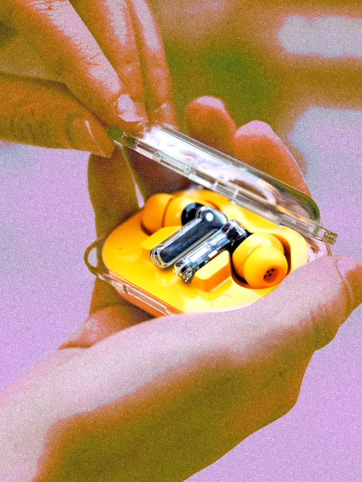 Inverse senior editor James Pero holding the $99 yellow Nothing Ear A wireless earbuds in his hand f...