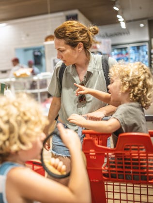 A mom shops at the grocery store with her kids.