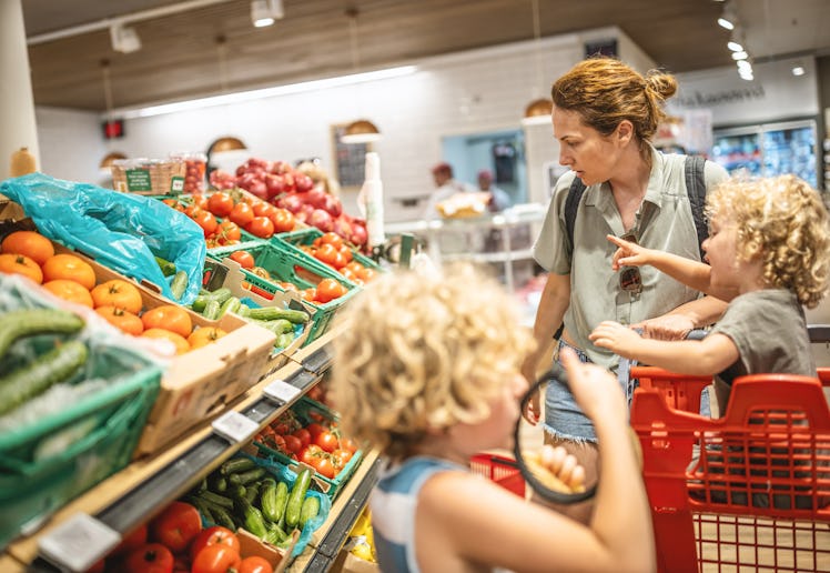 A mom shops at the grocery store with her kids.