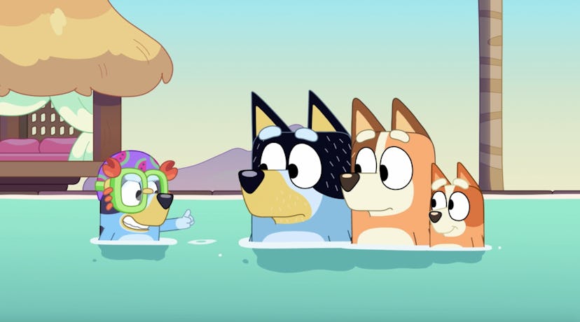 Bluey in a swim cap and goggles plays with Bandit, Chilli, and Bingo play in a pool.