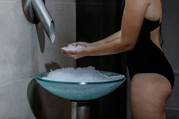 Young woman holding ice in a sink.