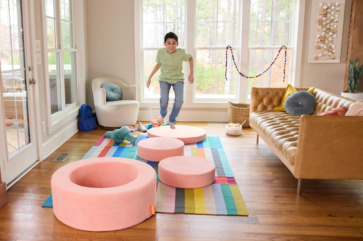 Child playing with Nugget Chunk play ottoman by jumping across them on the floor.