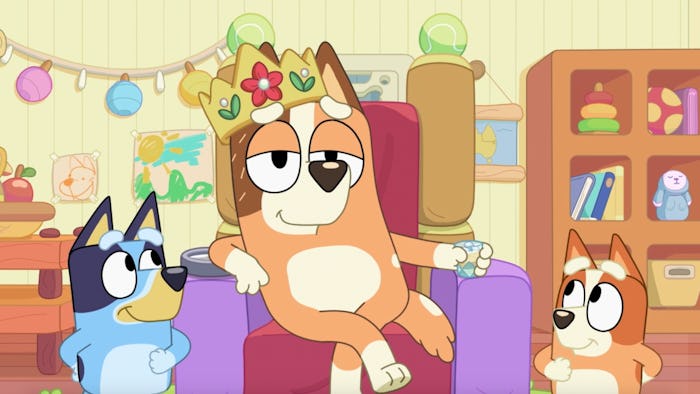 Chilli sits on a throne wearing crown, attended by Bluey and Bingo.